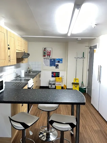 Kitchen in ensuite accommodation at City Campus, a sofa facing a flat television on the wall next to a side table with a microwave