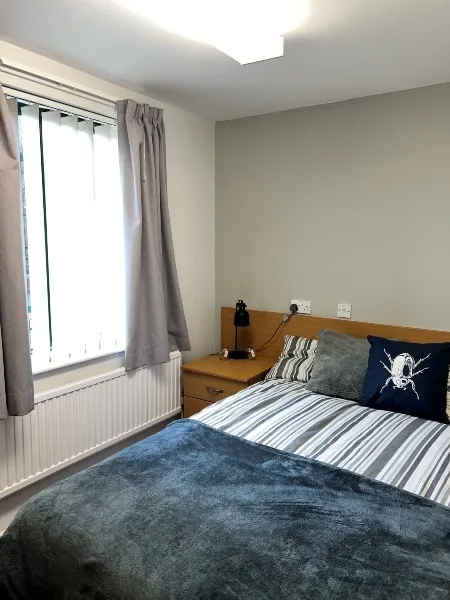 A bedroom in City Campus ensuite accommodation: a double bed with a window to its right