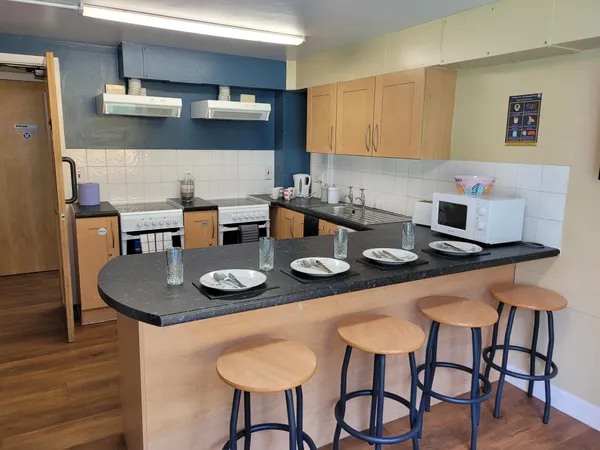 Photograph of Walsall Campus accommodation: a kitchen countertop with four stools seated beneath it, rows of cupboards and two ovens.