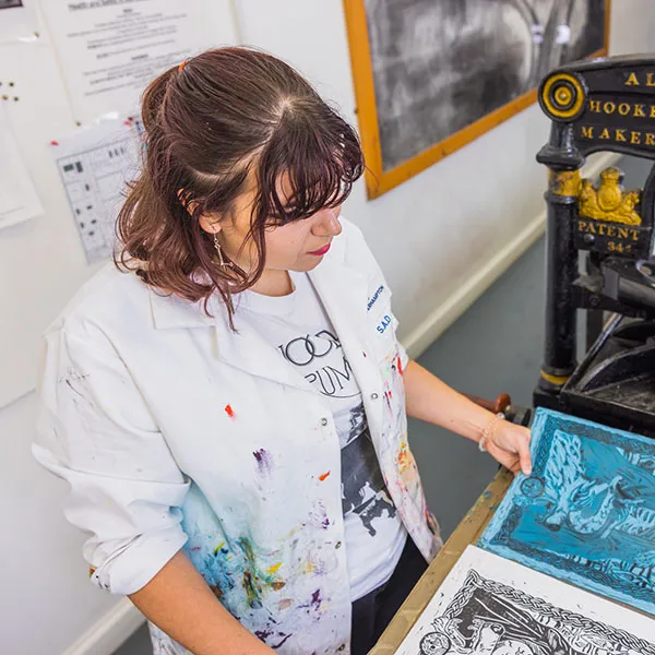 Female student looking at a finished linocut print in the Relief printing room