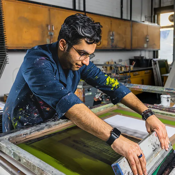 Male student screen printing in the screen printing studio