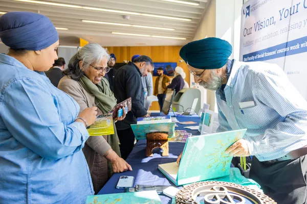 Thumbnail Image from the Research in Sikh Studies Conference June 2023 showing a pop-up stand being inspected by attendants