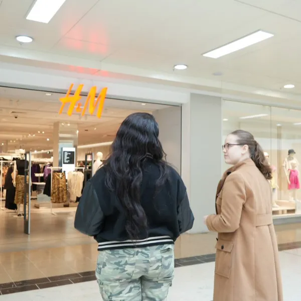 Two people in the Mander Centre standing outside the H and M storefront