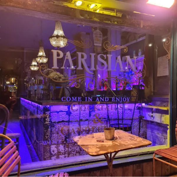 Exterior of the Parisian cocktail bar, with its branding in the window and purple lighting inside