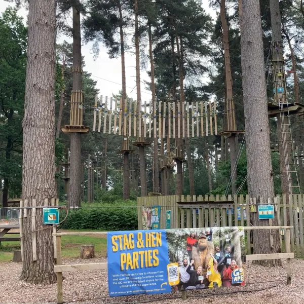 An outdoors area with seating and climbing structures, signage showing that the area is taking admissions for stag and hen parties
