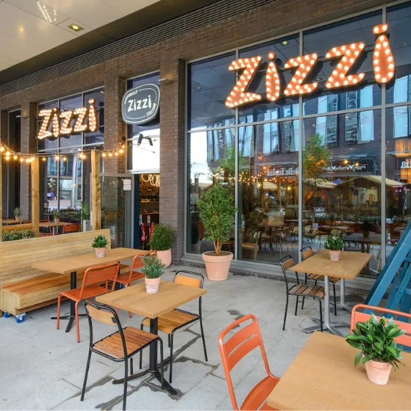 Zizzi outdoor seating: tables, chairs and benches arranged outside a restaurant front with prominent ZIZZI signage