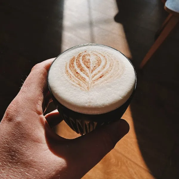 A coffee in a black mug with latte art