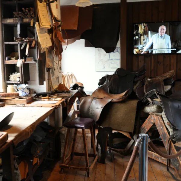 The leather museum: several saddles are out on display, cuts of leather hung up on the wall, a television screen playing a video in the background