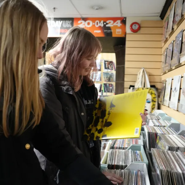 Two students in a record shop leafing through records and choosing favourites