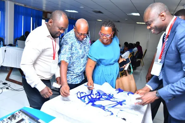 Photograph of four people around a table, writing on a sheet of paper next to an arrangement of blue ribbons.