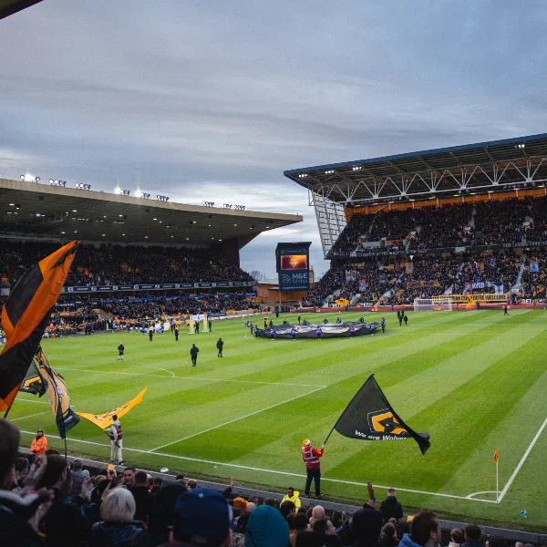 A match in the Molineux stadium, fans in the stands waving flags