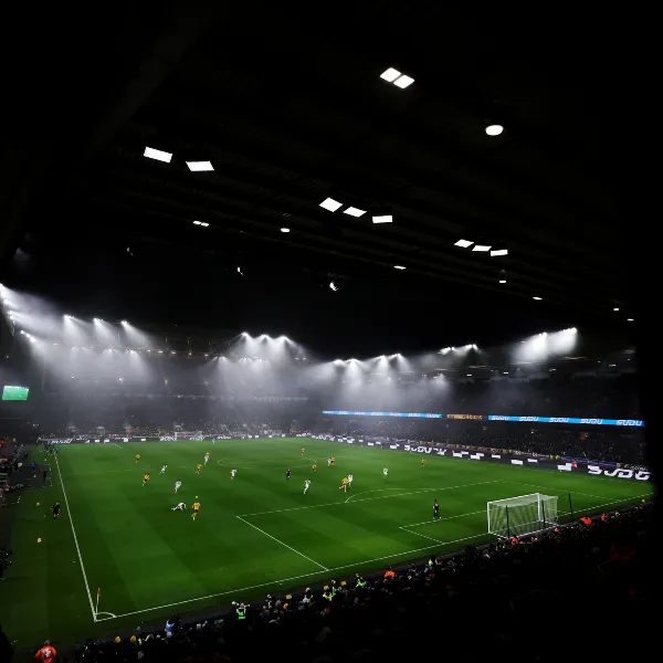 Floodlights shining on an ongoing game inside the Molineux stadium at night