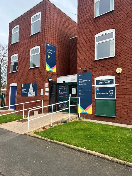 Exterior of the Accommodation Hub, a building with three floors and windows on each floor, signage identifying the building as the accommodation hub.