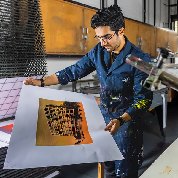Male student admiring their print in the screen printing studio