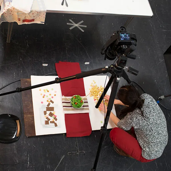 Photography student setting up a camera and a tripod in the main photography studio