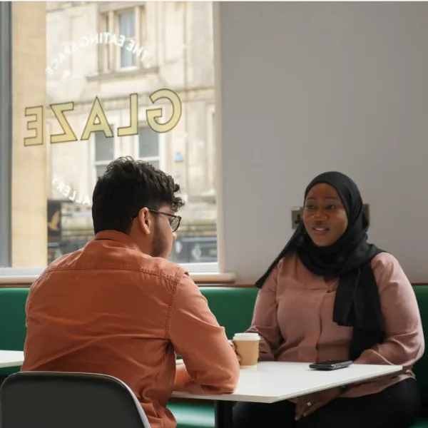 Two people sitting at a table inside the Glaze eating space