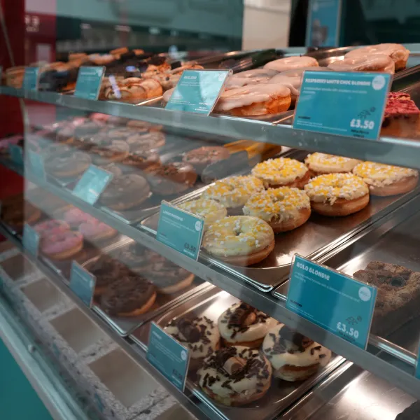 Shelves in Planet Doughnut stocked with different doughnuts and their price listings
