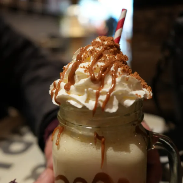 A drink with cream and a paper straw served in a mug stylised as a glass jar