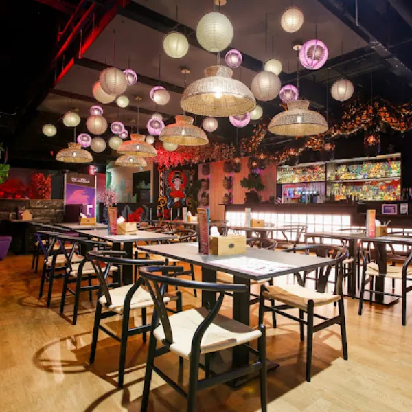 Tables and chairs in Putt Putt Noodle restaurant with overhead lights and lampshades