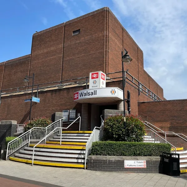 Walsall train station, stairs leading to a red brick building with train station signage outside